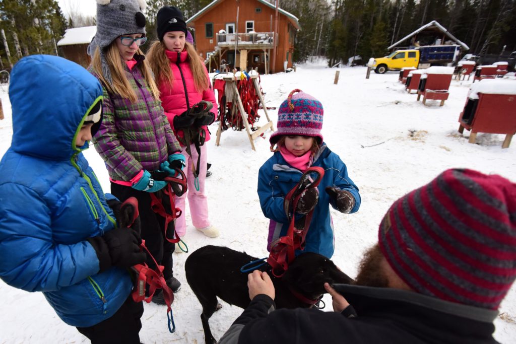 People standing around a dog in the snow.